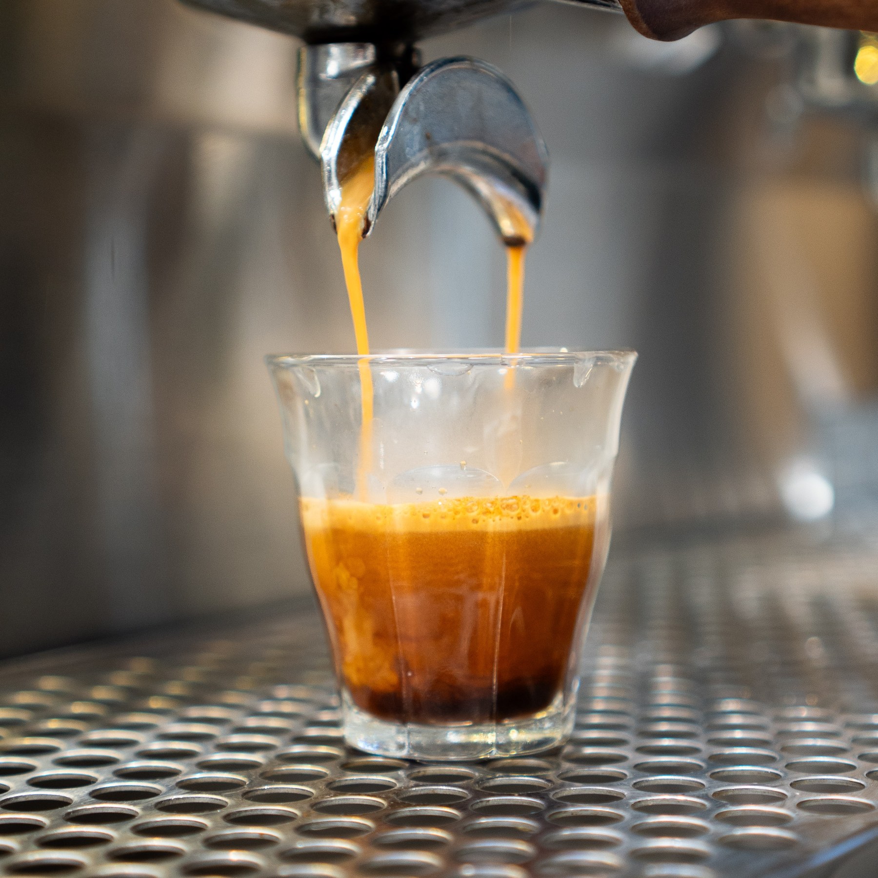 Espresso pouring from a machine into a clear glass.