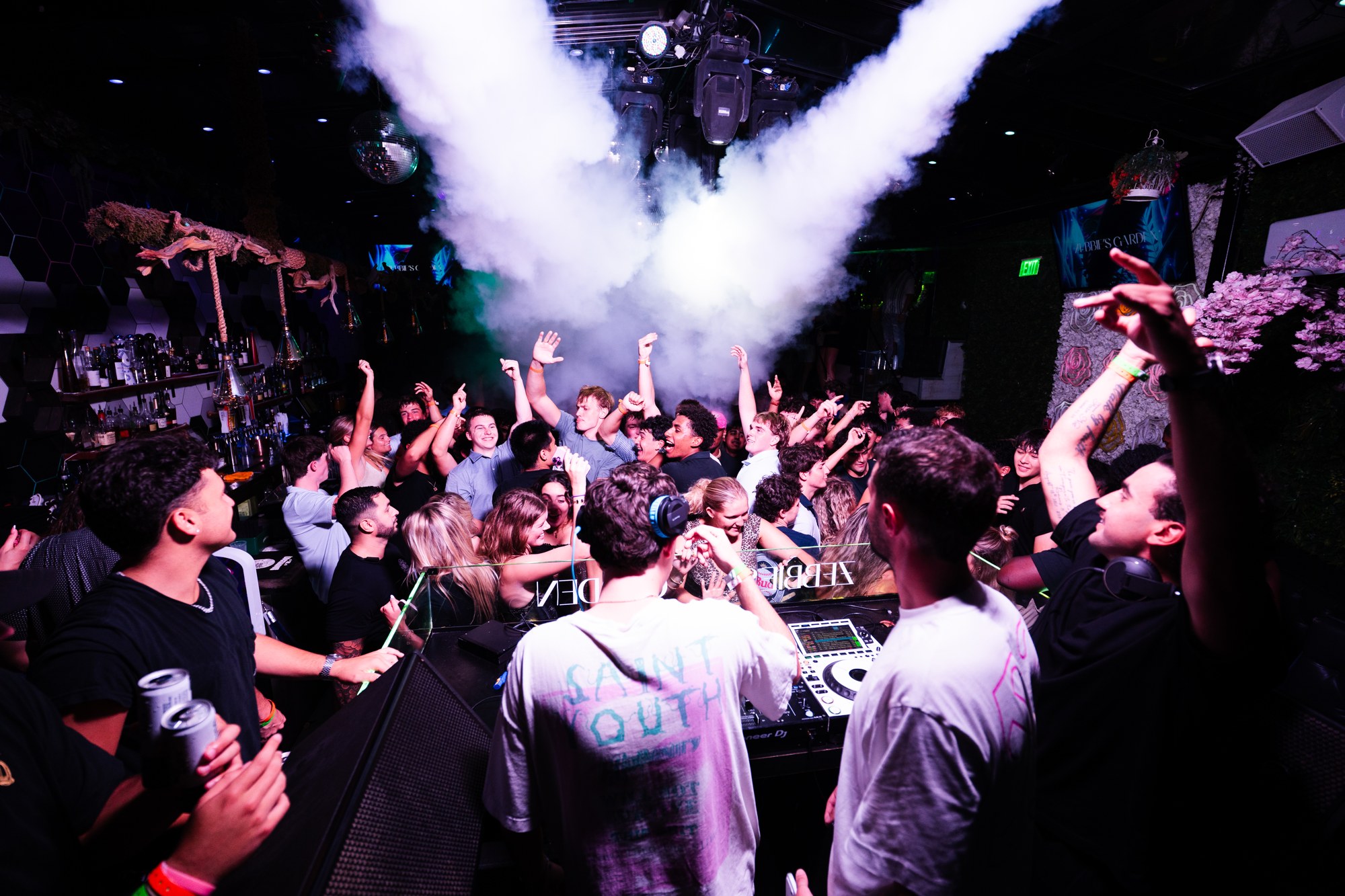 DJs and a cheering crowd beneath a plume of stage fog at Zebbies