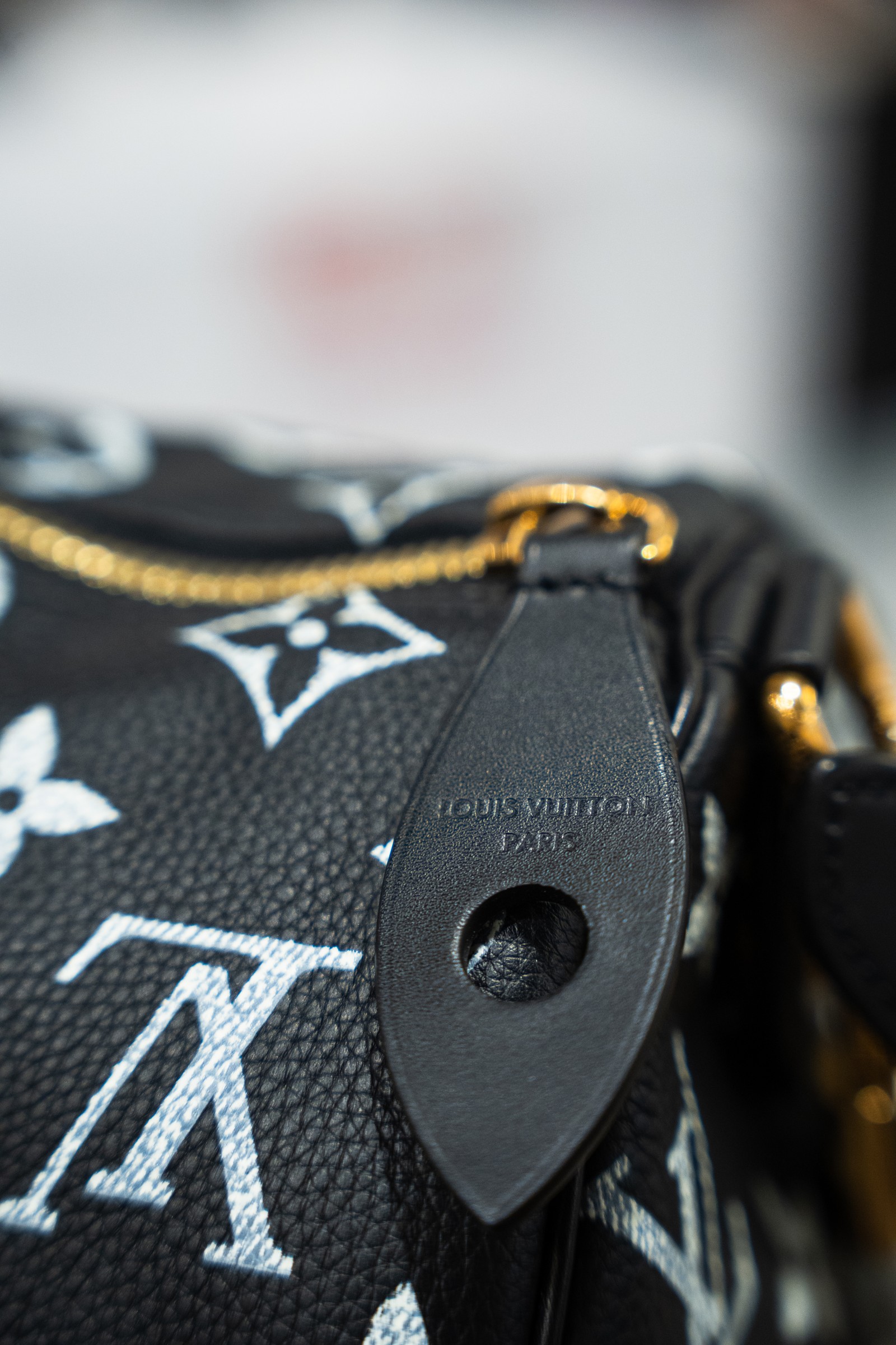 Close-up of a black Louis Vuitton monogram bag and leather tag.