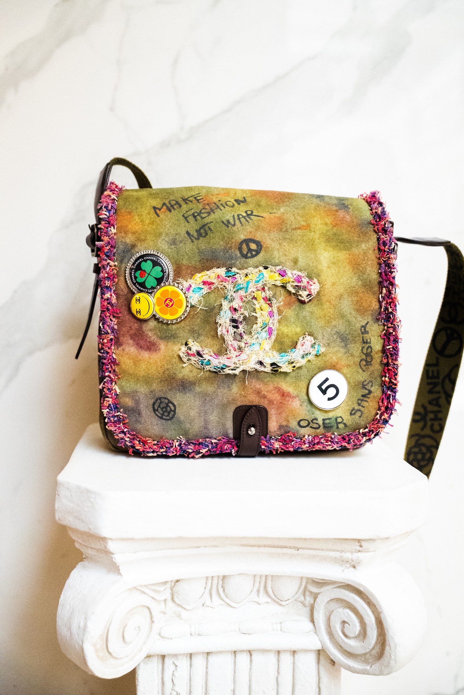 Multicolor Chanel textile shoulder bag on a white sculpted pedestal.